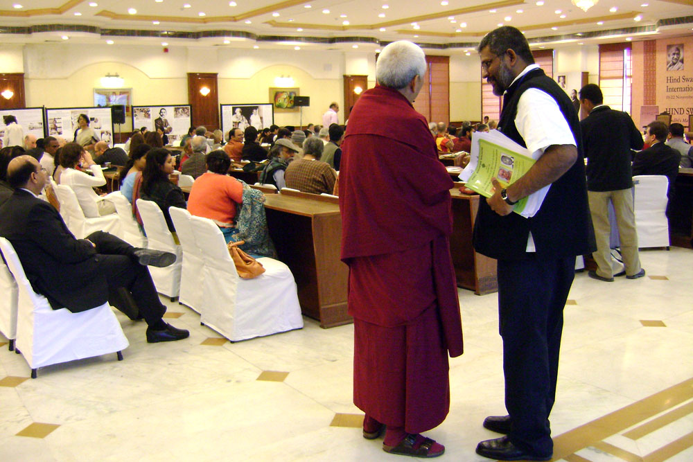 a man dressed in red and black is handing soing to a priest