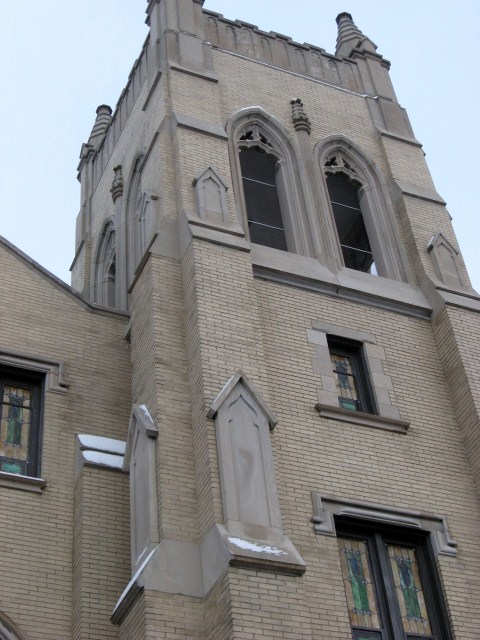 a grey church building with multiple windows and a roof
