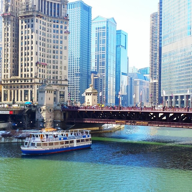 boats sailing under a bridge over a river in a city