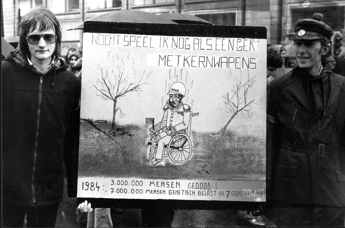 black and white pograph of three men holding signs in front of some buildings