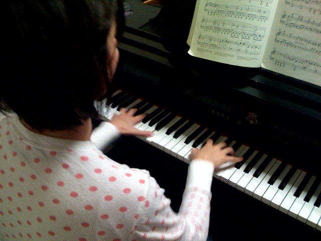 a girl playing the piano by a piano sheet
