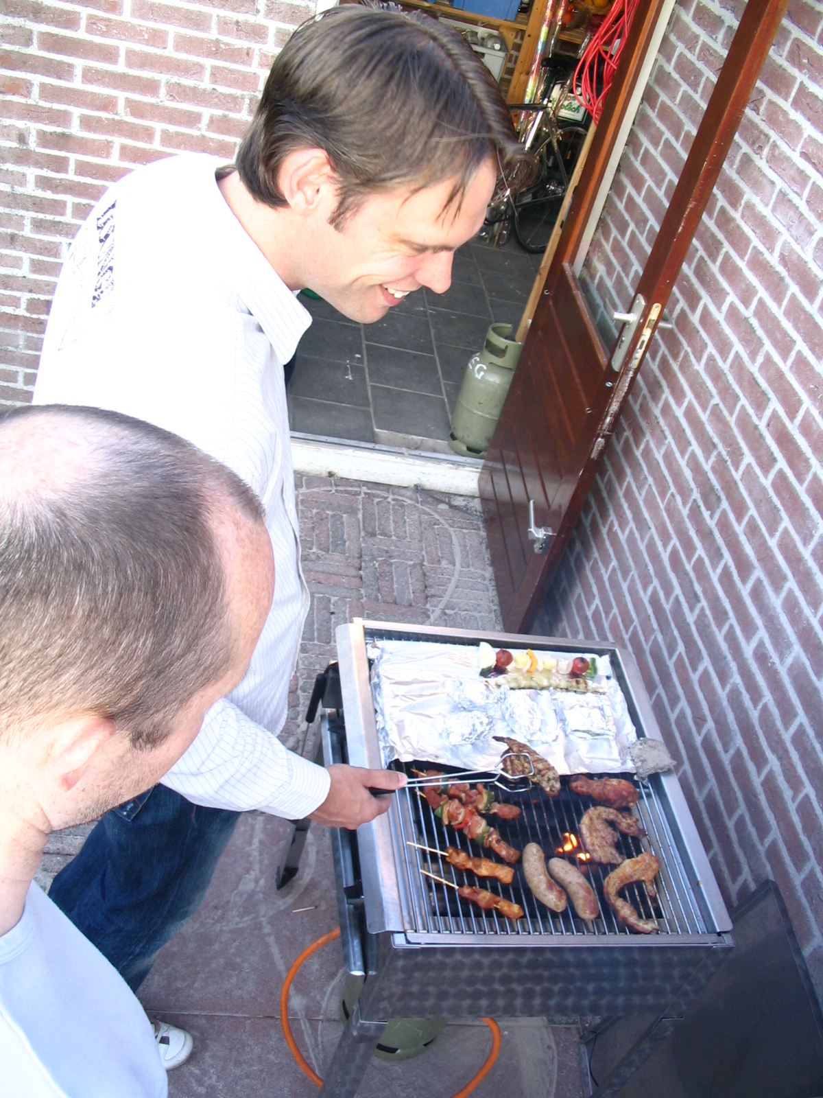 a man is pointing at a grill with meat on it