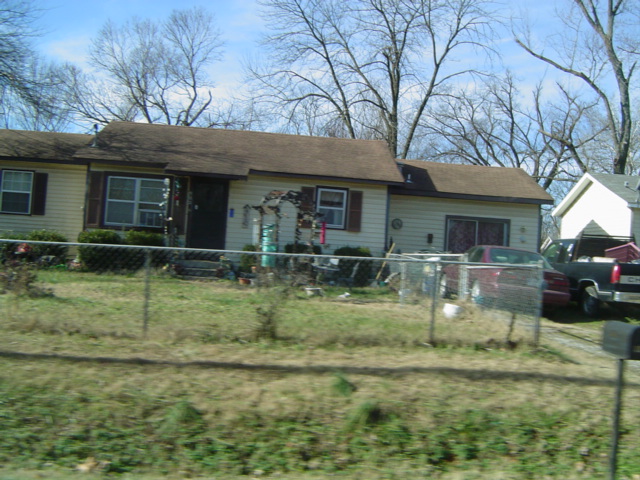 a white house behind a fence and trees