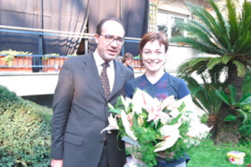 a man and woman pose together holding vases filled with flowers