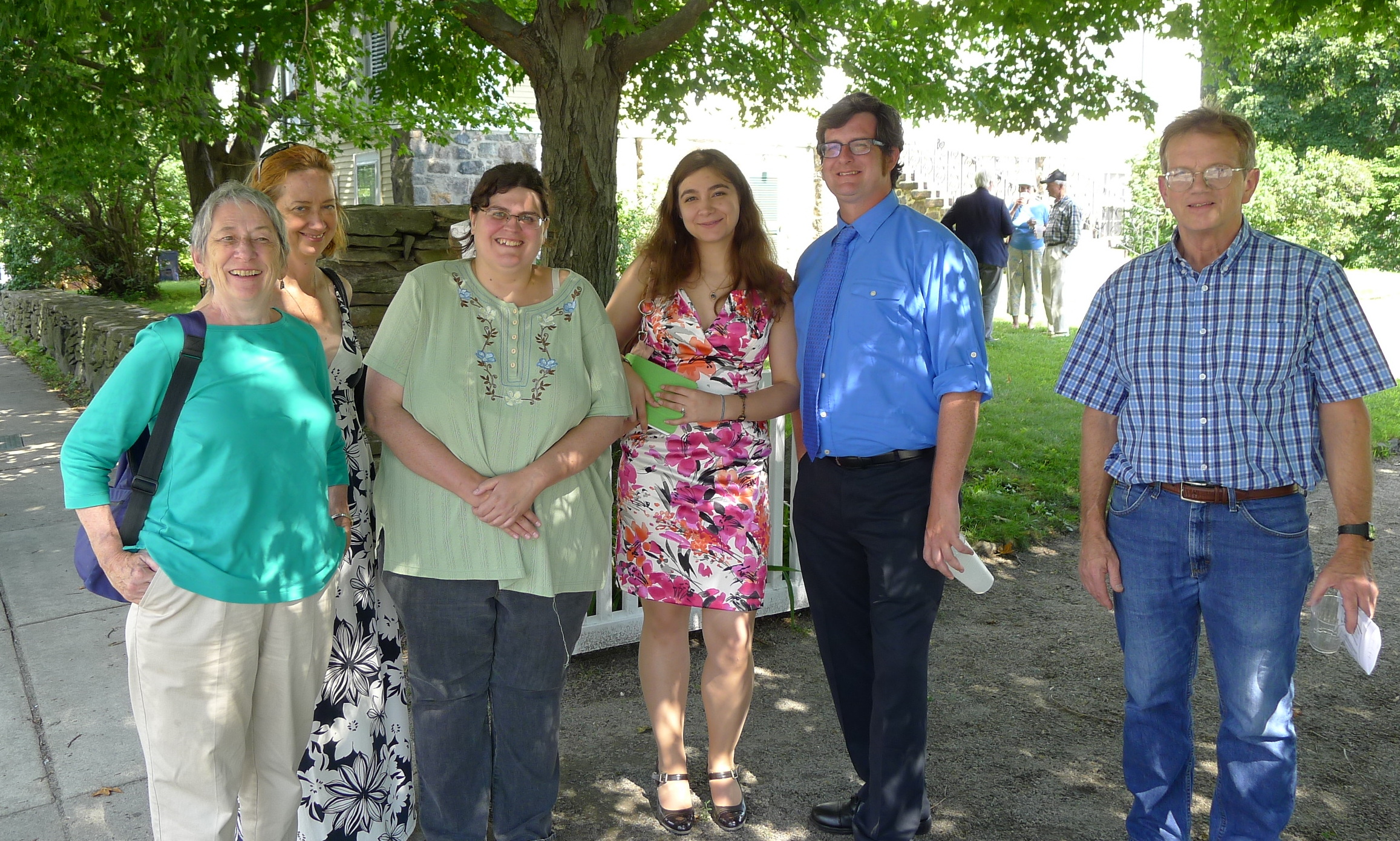 group of people in blue shirts posing for picture under trees