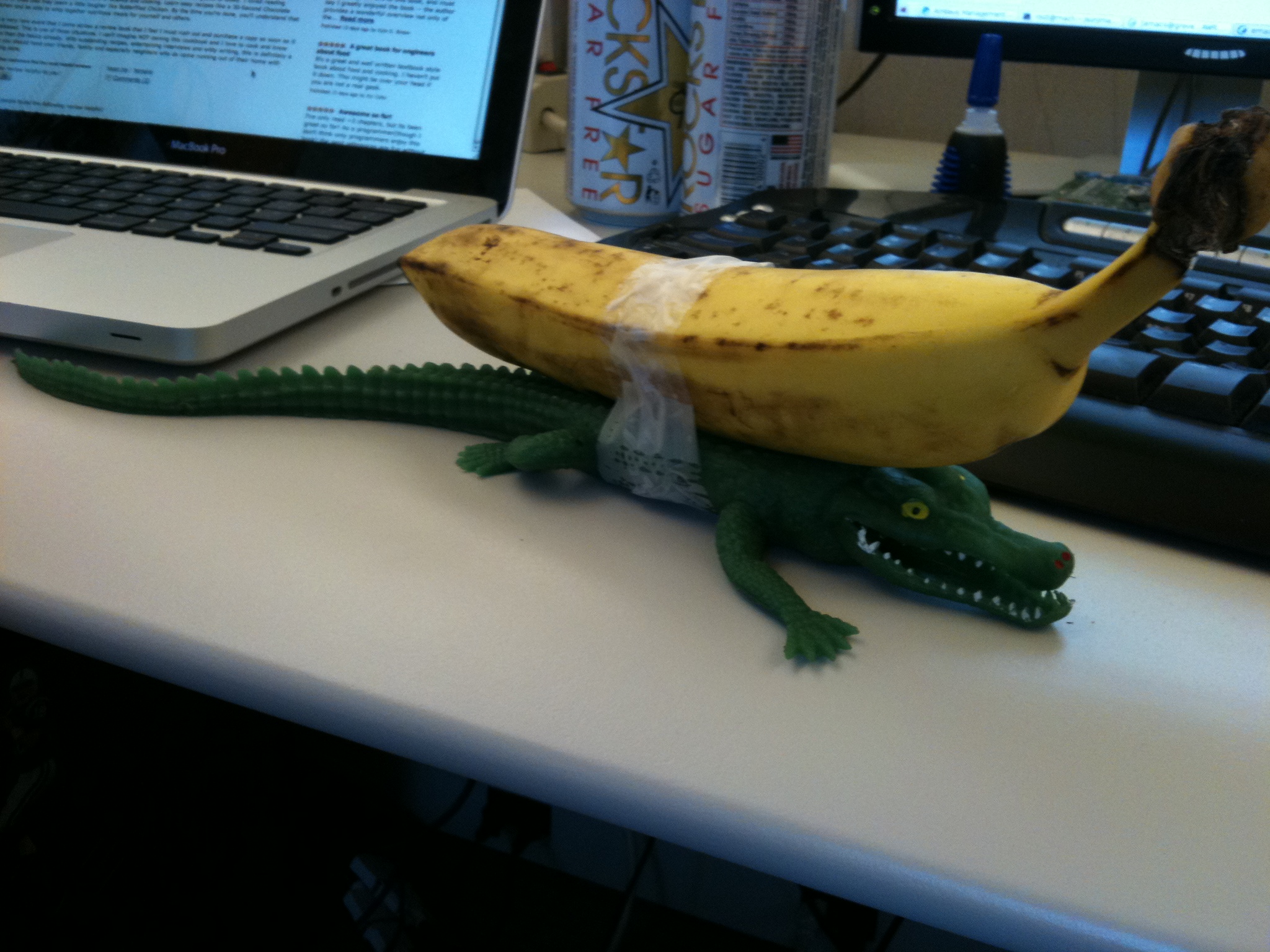 banana in front of laptop on desk with fake lizard like tail