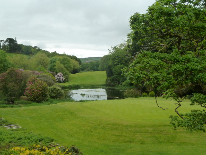 green golf course surrounded by wooded areas with pond and trees