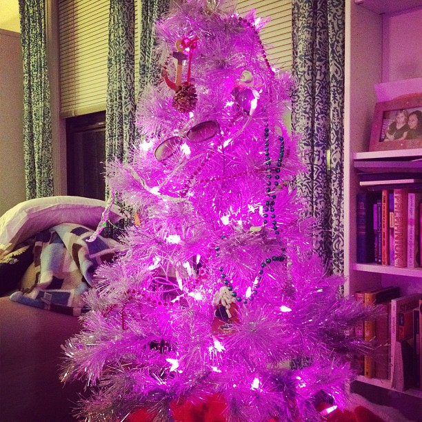 purple tinsel covered christmas tree with a red bow