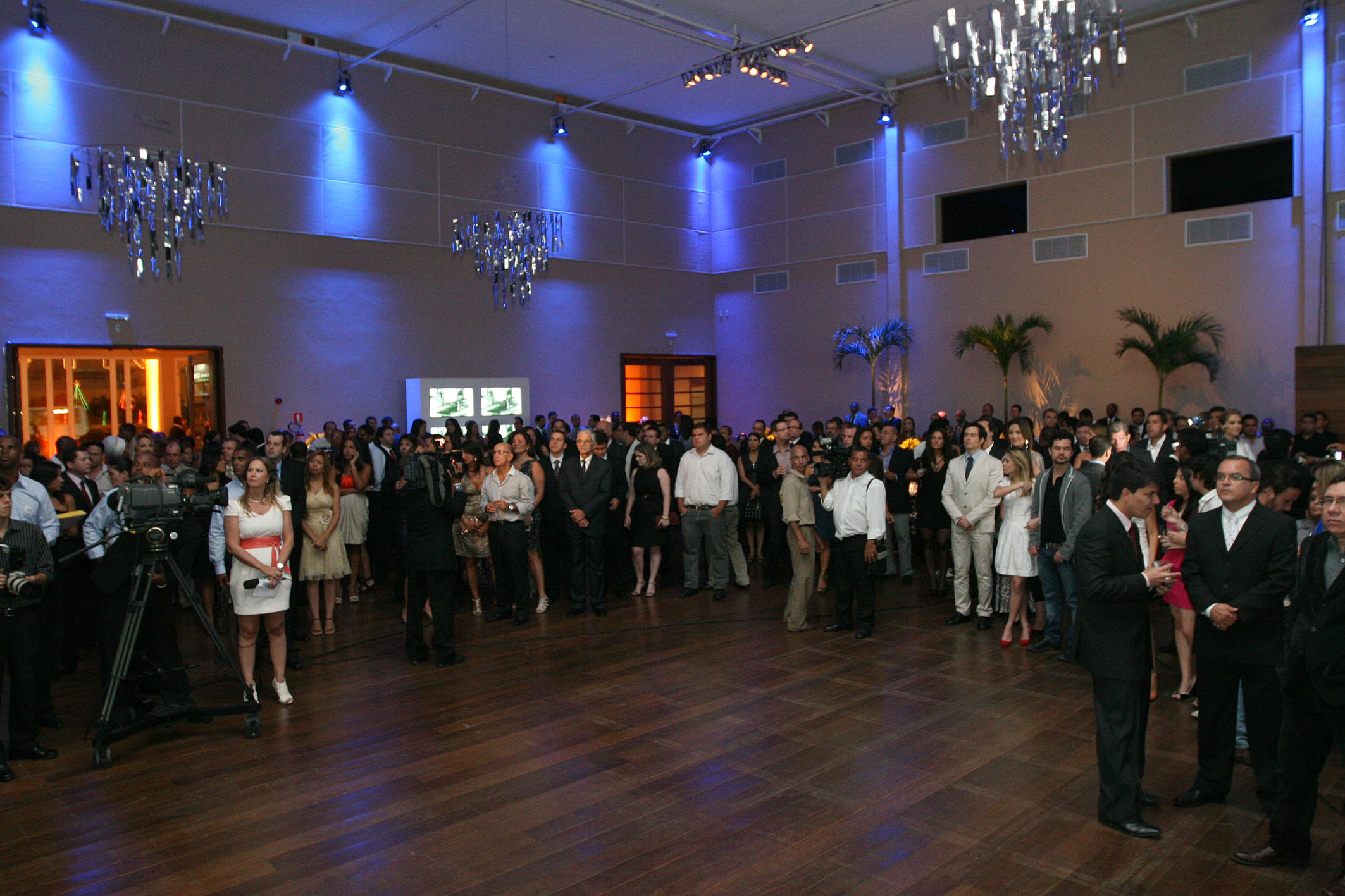 large gathering of people standing around in an indoor ballroom