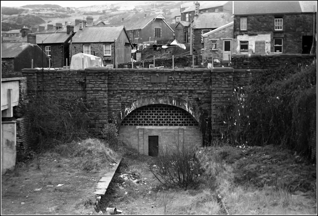 a very old bridge over a street by a lot of houses