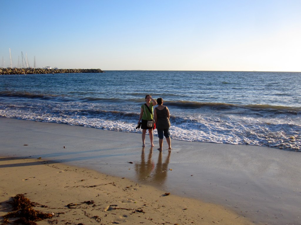 two men standing on the sand near the ocean shore