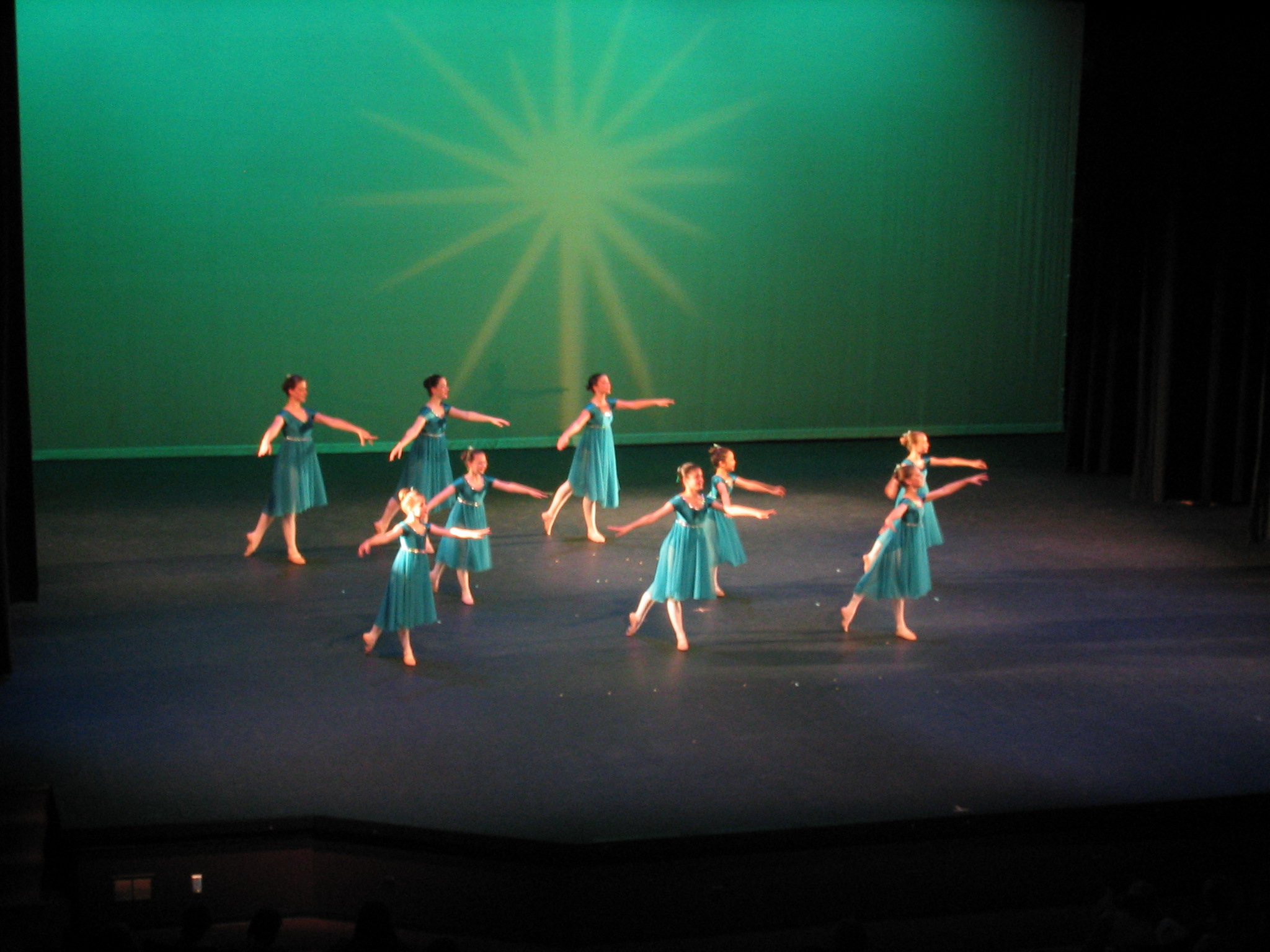 there are girls in blue dresses dancing on the stage