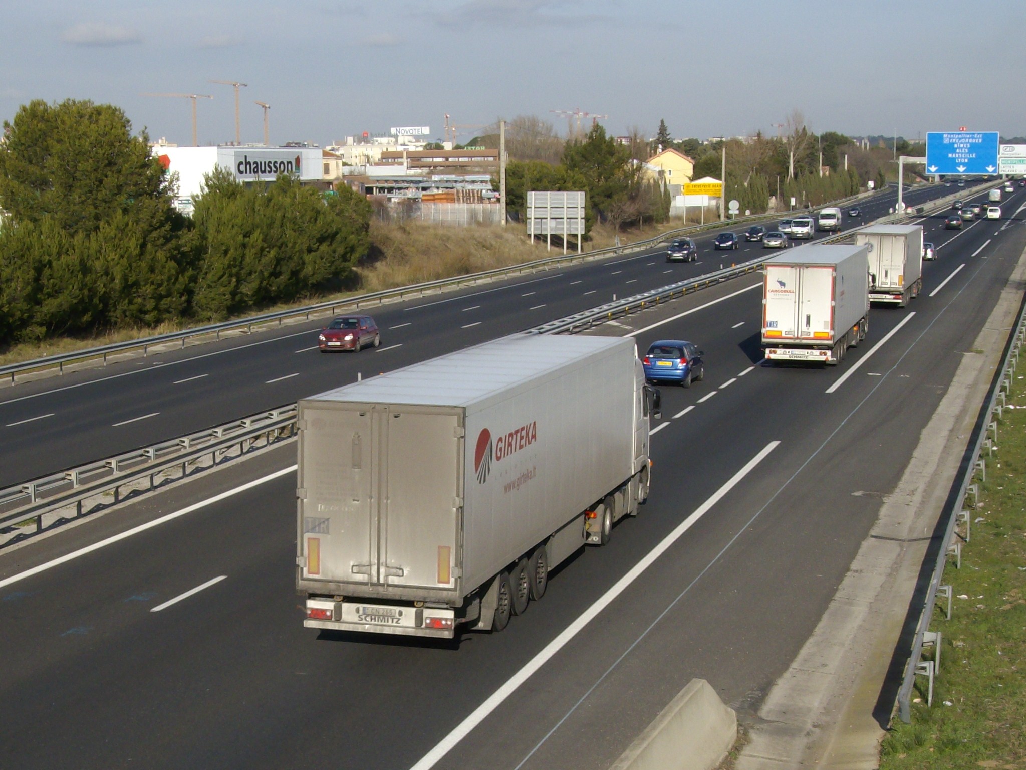 three trucks on road with other traffic in distance