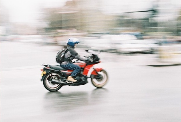 man riding a motorcycle on the wet city street