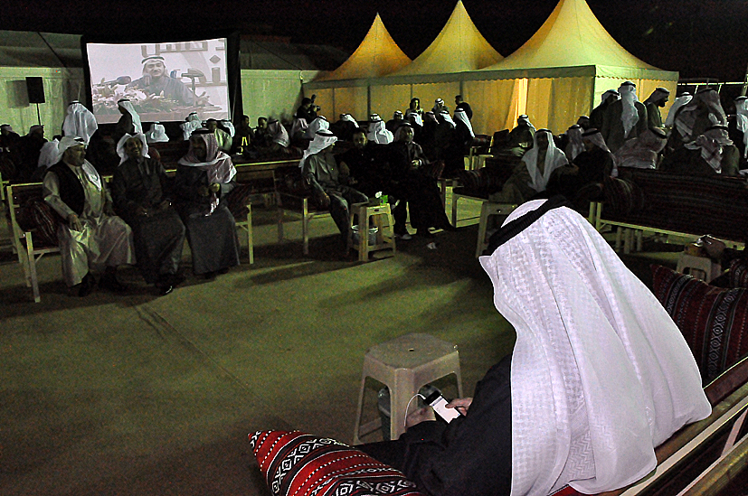 a large crowd in a building with chairs and white tents