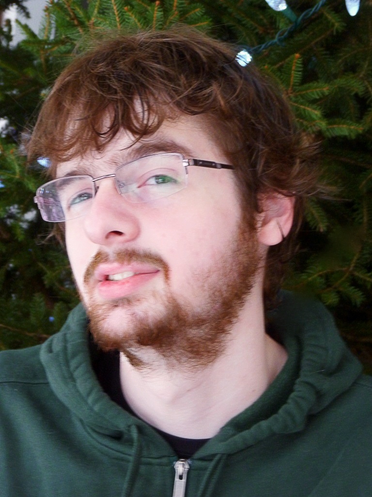 a man with glasses and a beard stares to his left