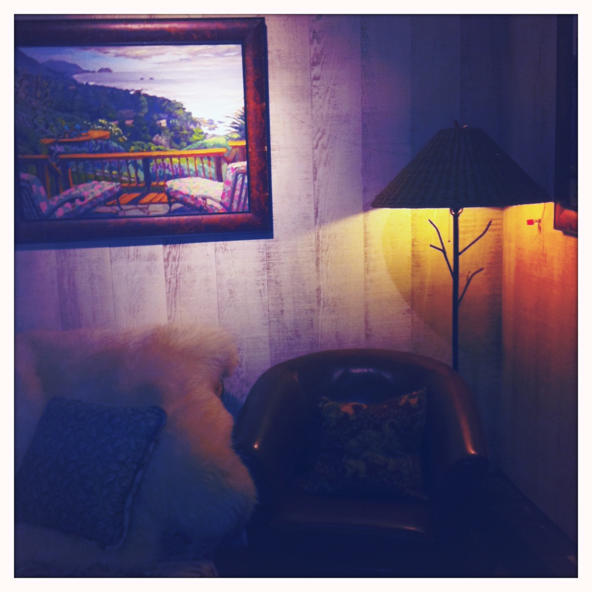 a pograph of some artwork on the wall behind a chair and a lamp