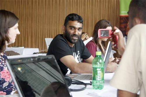 people sit at tables in front of laptop computers