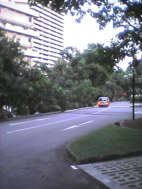 a van is driving through a residential area with large buildings behind it