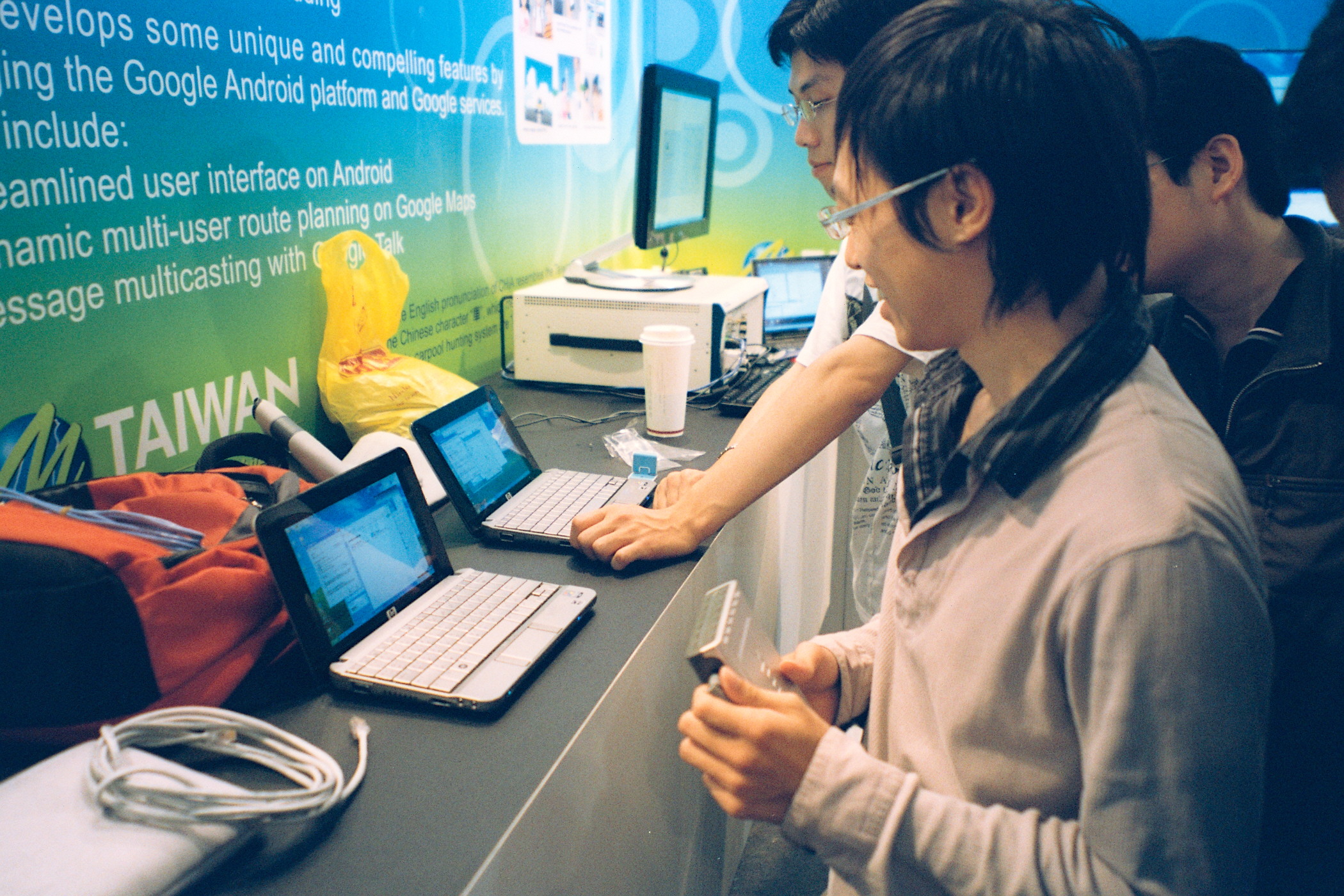 two young men are sitting at a desk with computers