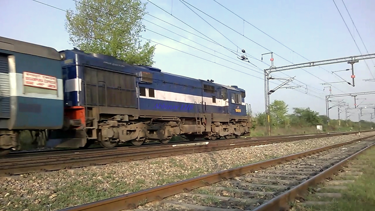 a blue train moves along the railroad tracks