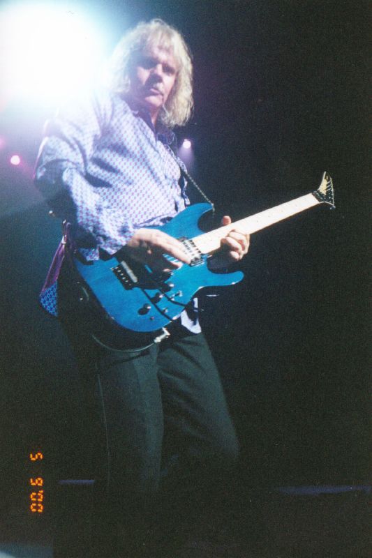 a man in a tie playing a blue guitar