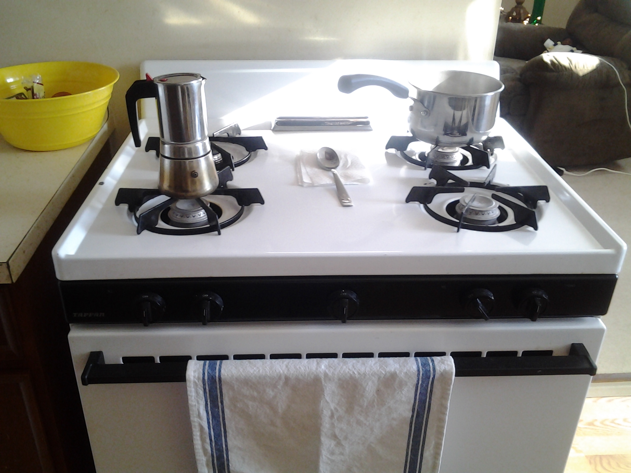 a stove top oven with two burners, a tea kettle and a towel hanging on it