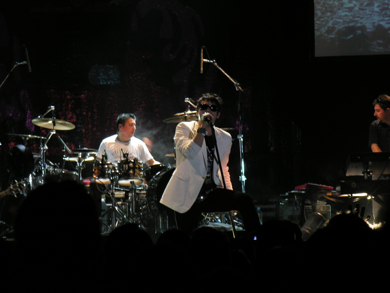 two male and female drummers playing instruments while people watch