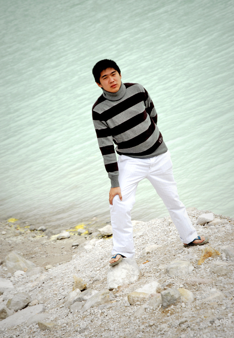 a man in white pants is standing near water