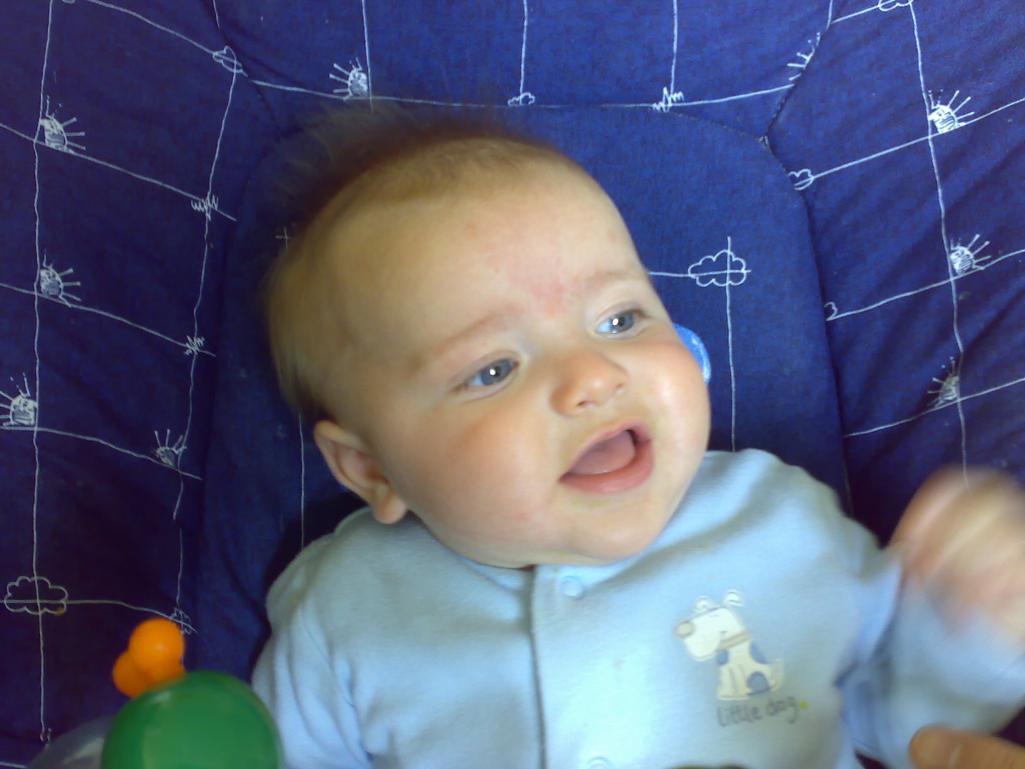 the baby is happy and he seems to be in his high chair