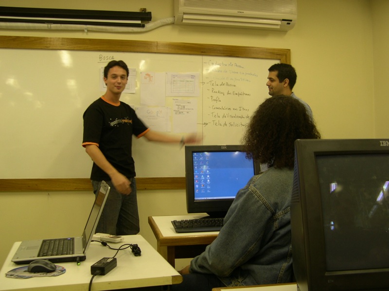three men in a classroom with laptops and monitors