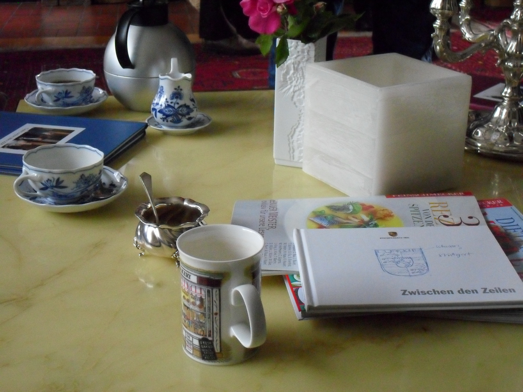 an assortment of tea cups, books and bookends on a table