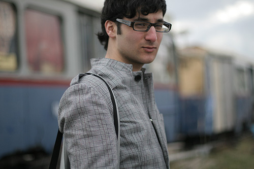 a man wearing glasses and holding onto a cross - body bag