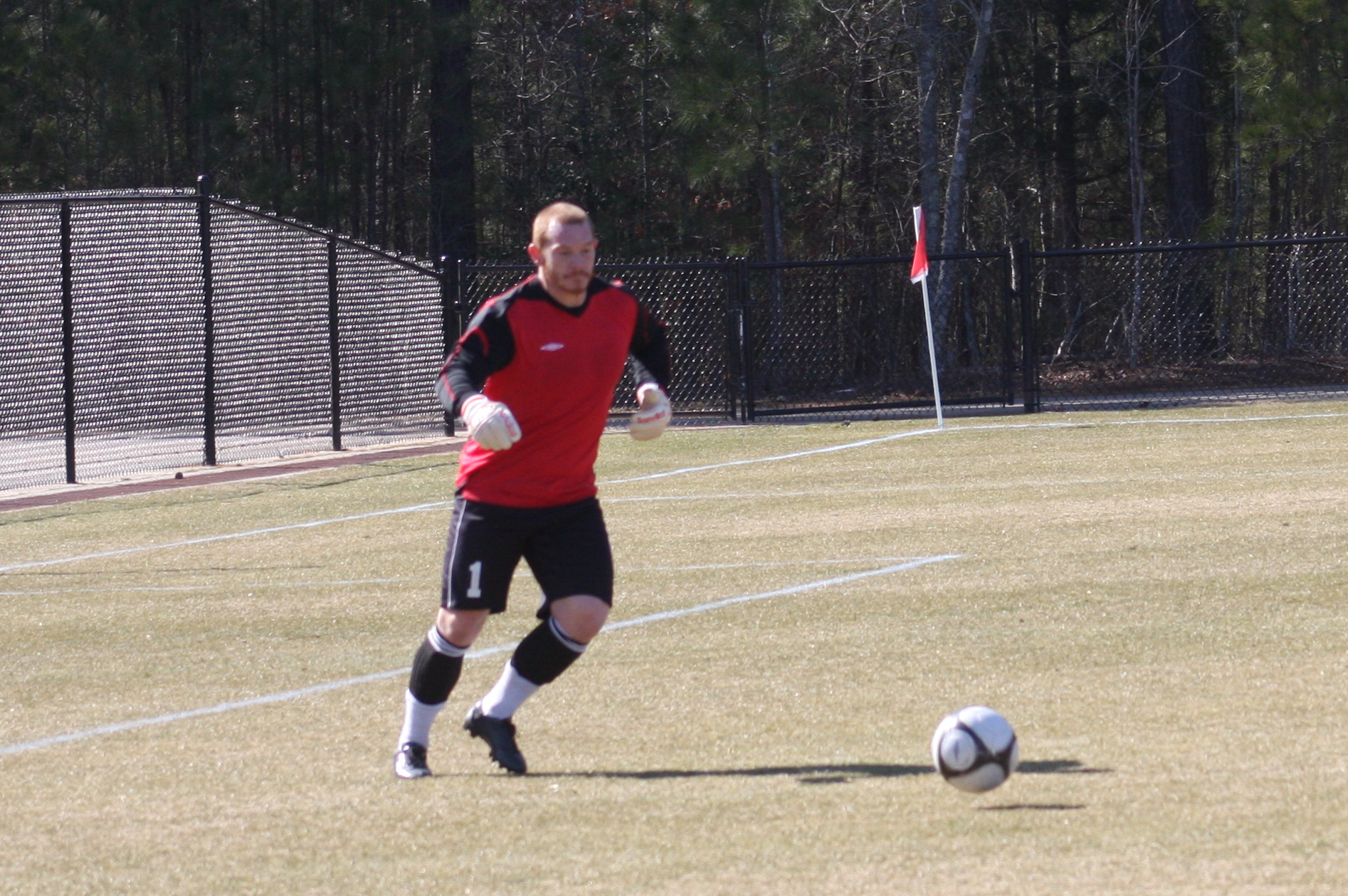 a young man standing on top of a grass field holding a soccer ball