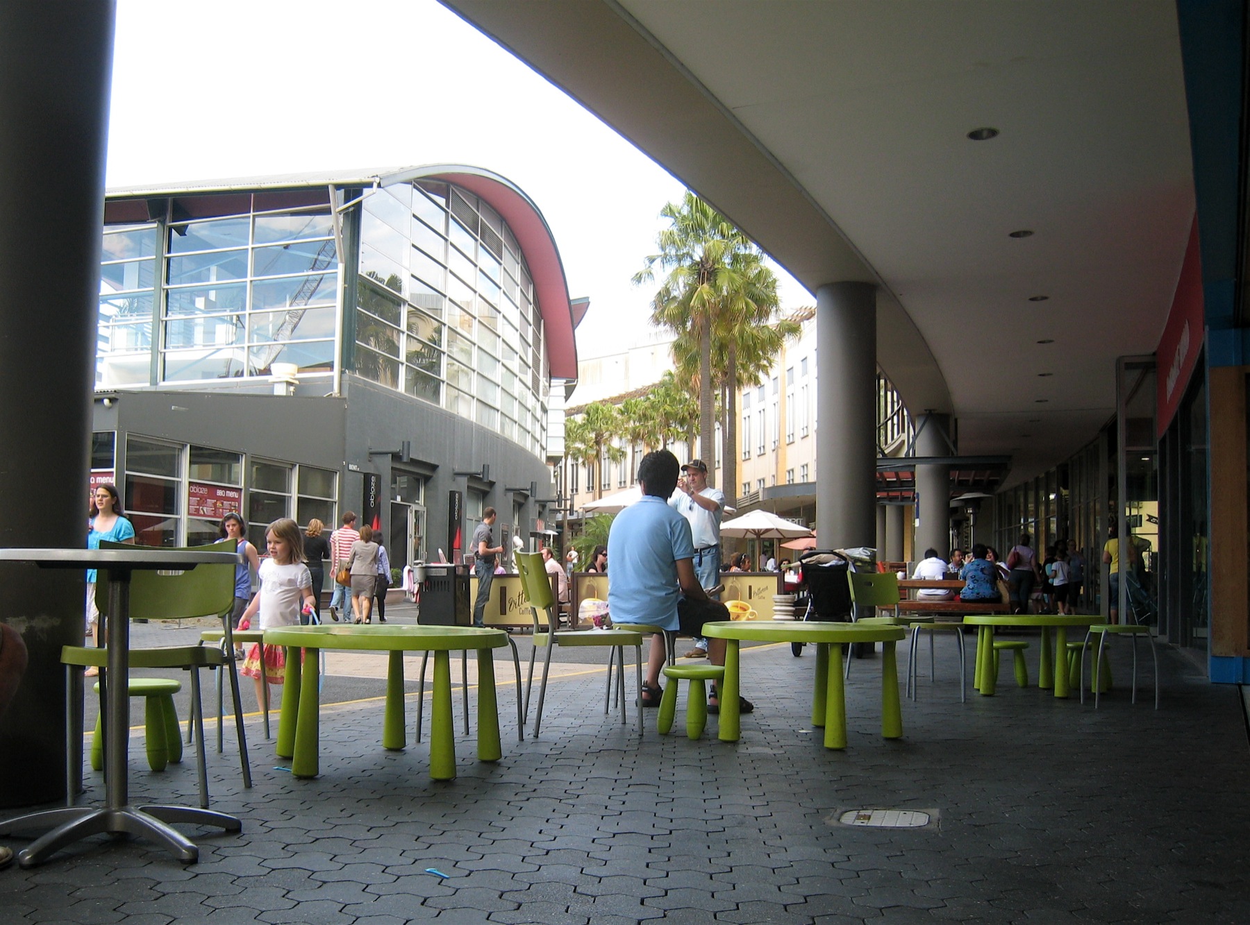 a city sidewalk with many people on benches