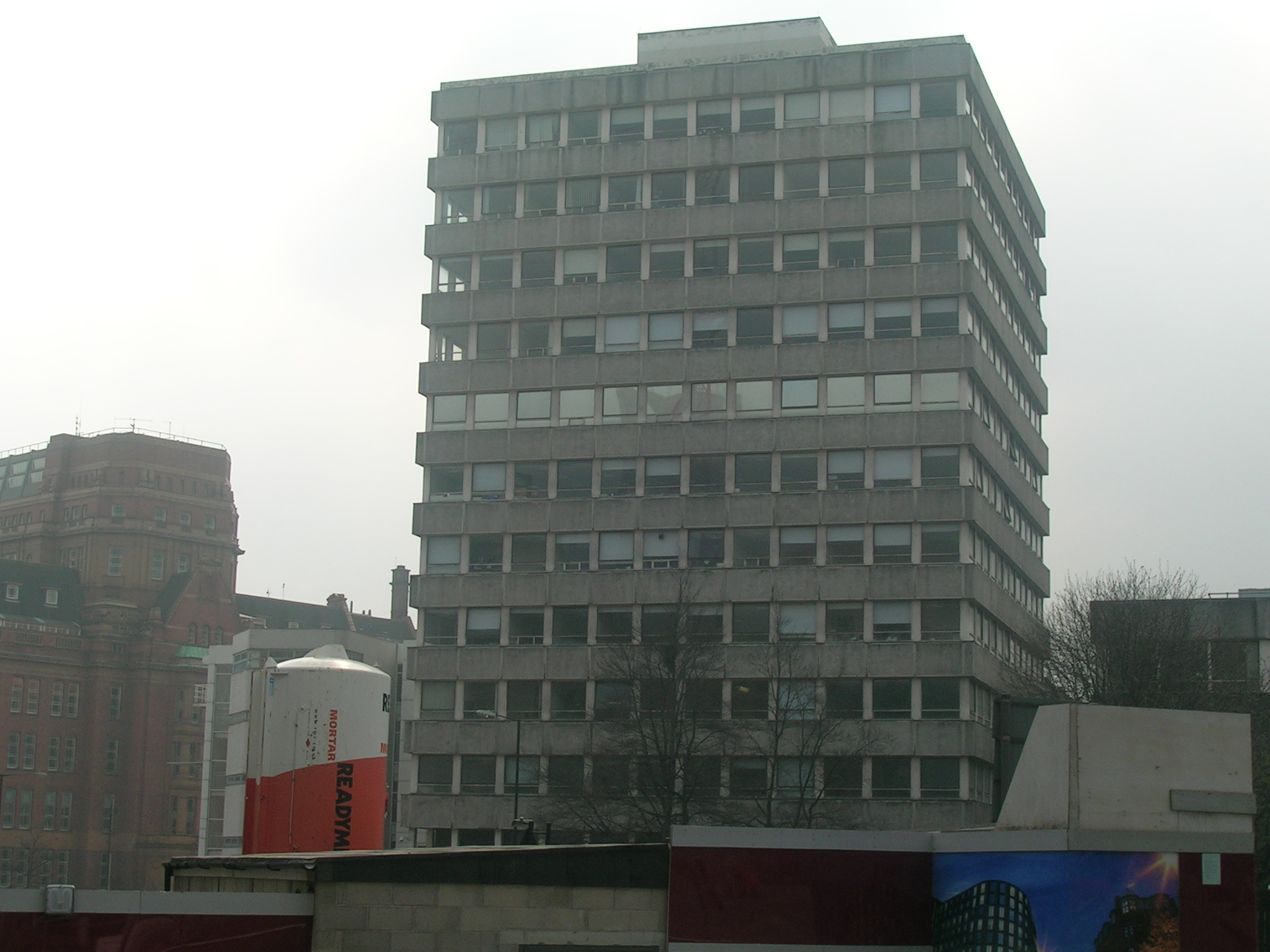 some very big buildings by the street with a lot of windows