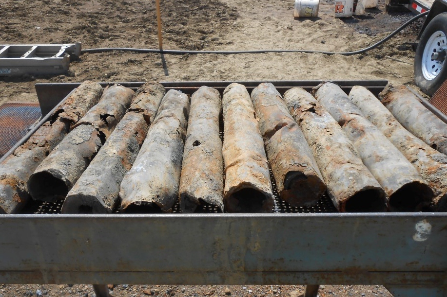 pipes sitting in the sand next to an industrial machine