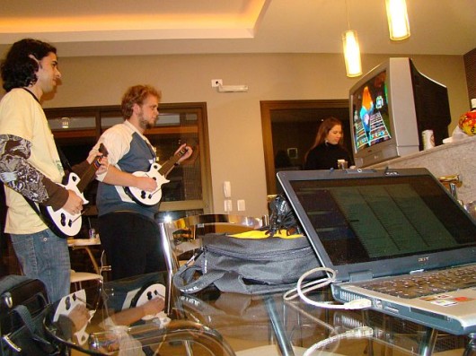 two men playing guitar in front of the television