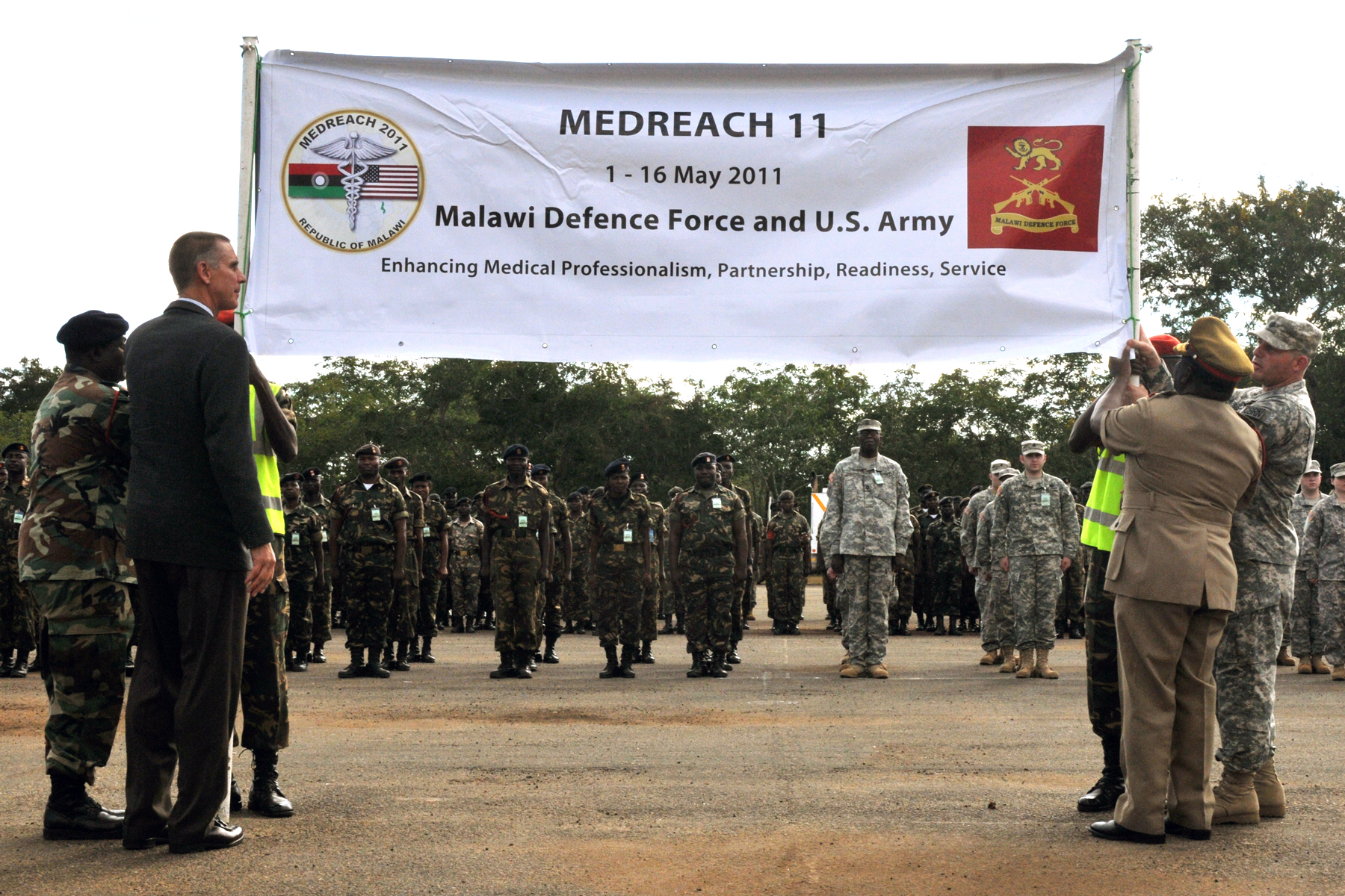 a man in suit saluting people standing by a military banner