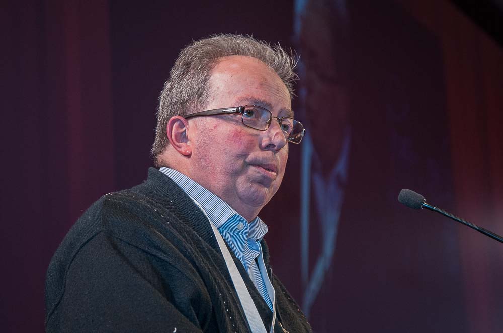 man wearing eye glasses speaks into a microphone