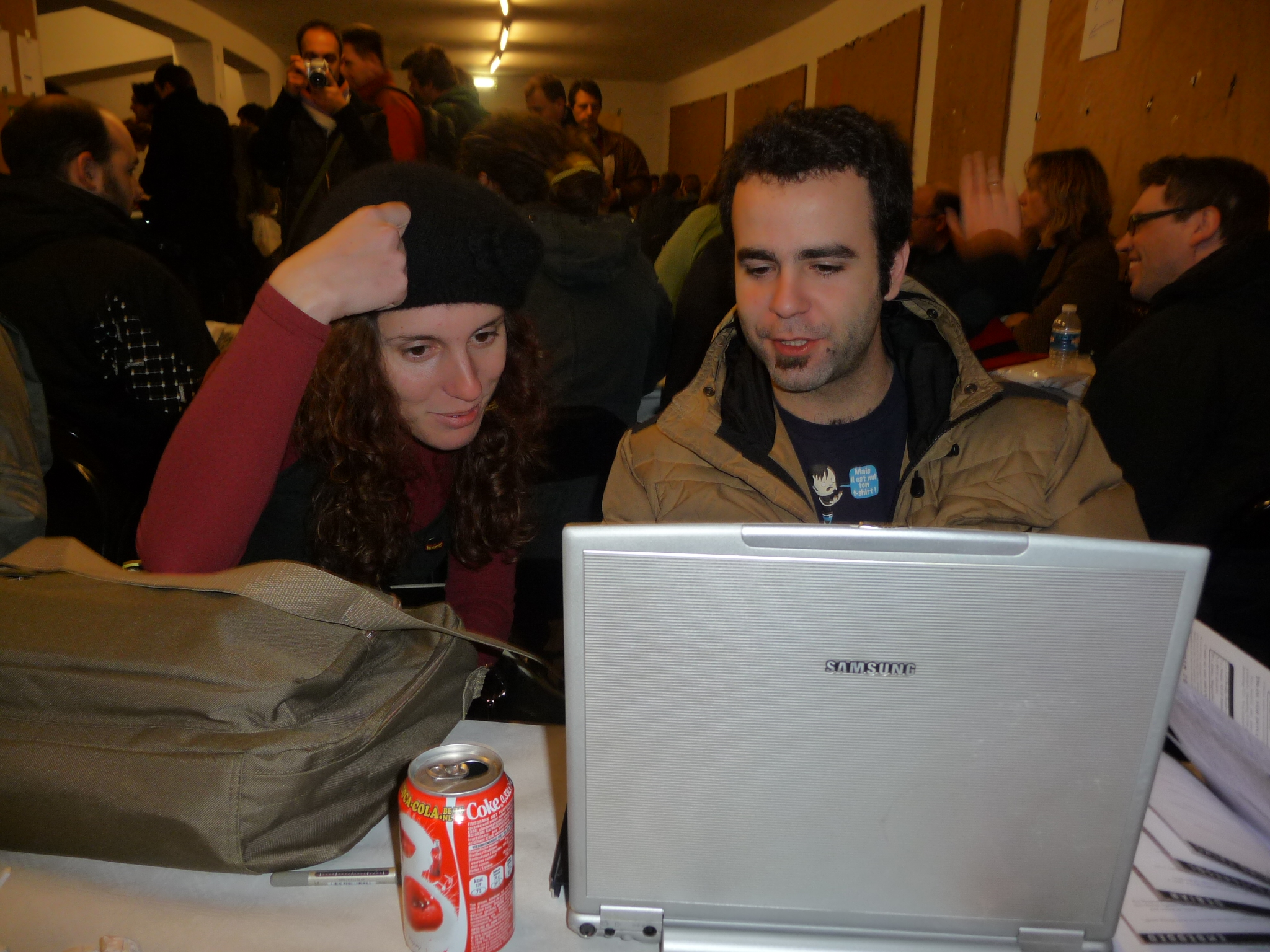 a woman and man are looking at a laptop