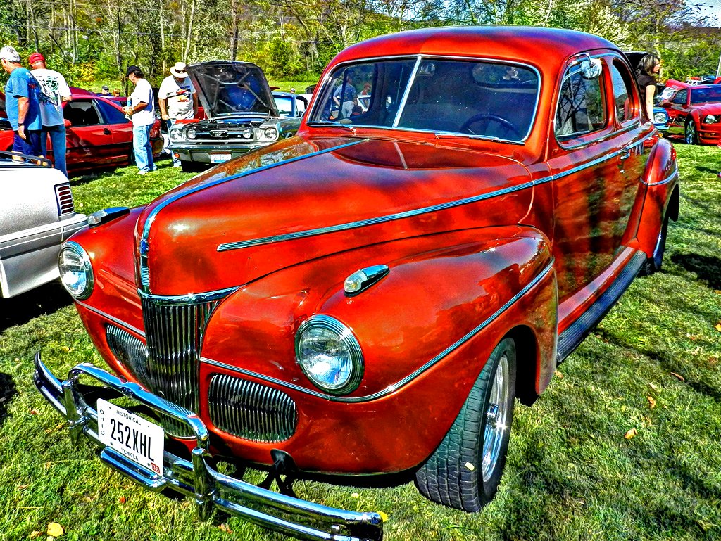 an older red car is parked in the grass