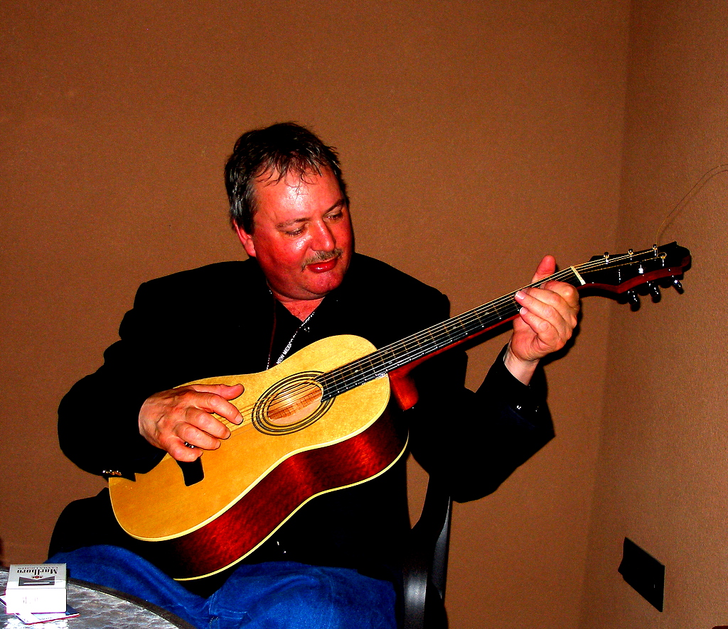 a man sitting down with an acoustic guitar