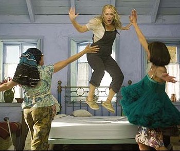 two women are jumping on a bed and one girl is in the air
