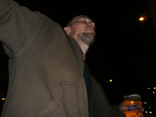 a man drinking beer from a beer can at night