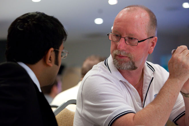 a man talking to another man who is wearing glasses