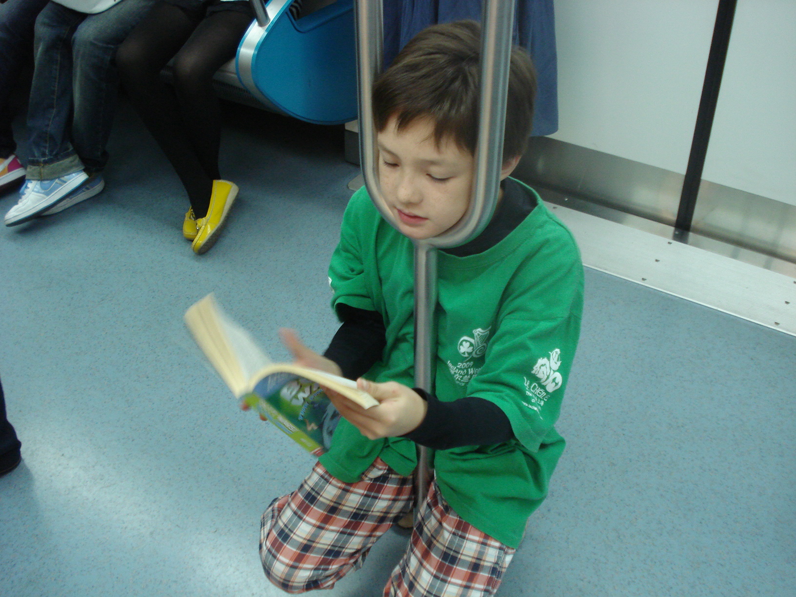 a small boy sitting on a bus reading a book