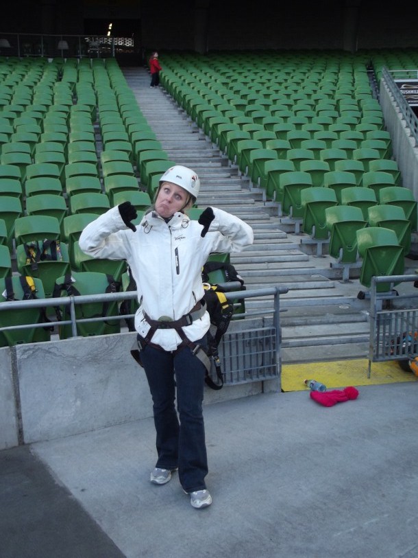 a woman in a white jacket is standing next to a large empty bleacher