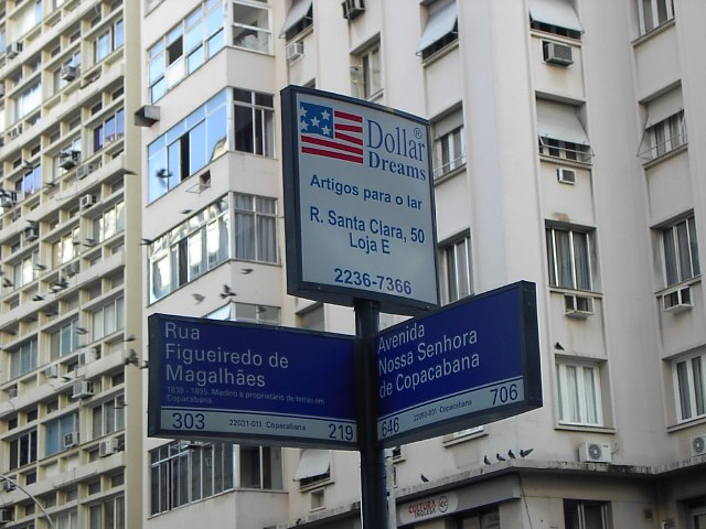 two street signs are displayed in front of several buildings