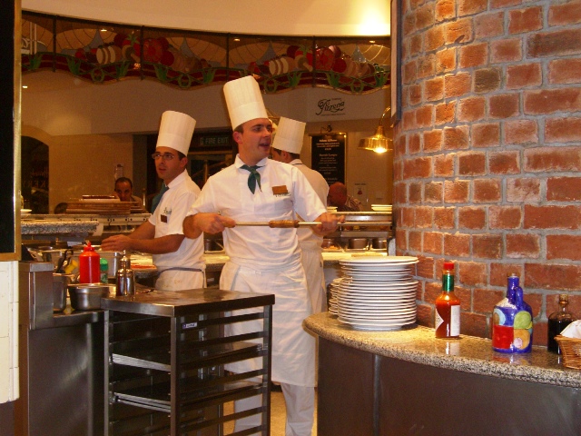 two men in chefs uniforms and hats standing near shelves